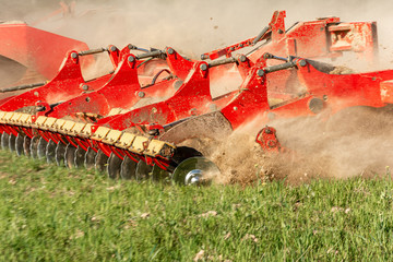 Agricultural equipment shreds the plowed land. A crawler tractor pulls a harrow to loosen the soil...