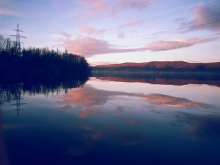 peaceful water close to the forest in spring season. calm lake reflecting clouds
