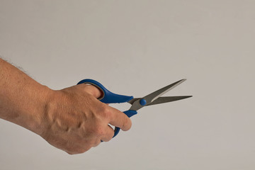 Hand holds scissors. Scissors are divorced and ready to cut.