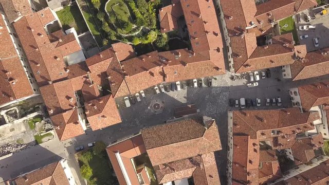 Top down aerial view of a small historic town Venzone in Northern Italy with red tiled roofs of old buildings.