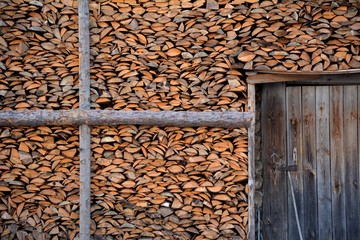 sawn boards or pieces of wood are stacked against the wall of the entrance to the building. wood texture, firewood
