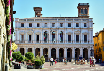 Bergamo / Lombardy, Italy - Biblioteca Civica Angelo Mai, occupy the Palazzo Nuovo di Bergamo on the Piazza Vecchia, a white building, people are walking in the square in front of it.