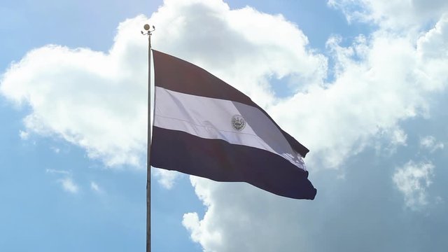 Bandera hondeando close up acercamiento a gran bandera El Salvador nubes y cielo
