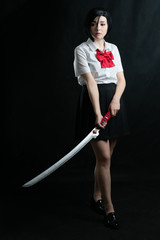 Girl with a katana in a school uniform. Cosplay. On a black background studio shooting. in full...