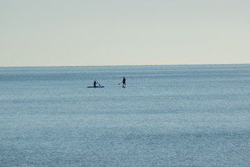 Fototapeta na wymiar Silhouettes of surfers on blue sea background