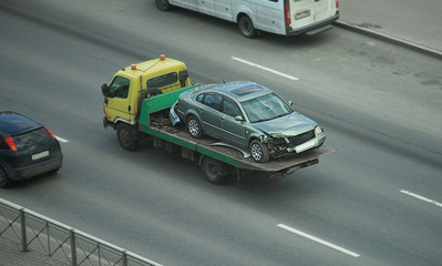 Fototapeta na wymiar A tow truck in the city carries a broken car after the accident