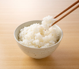 Scooping rice with chopsticks against a wooden background