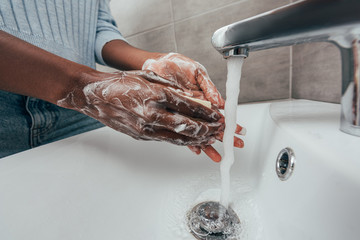 cropped view of african american woman washing hands with soap