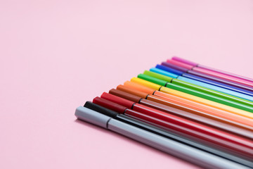 Fototapeta premium .Colored felt-tip pens on a pink background. A set of markers for drawing, creativity, hobbies, classes. Angle view, close-up, macro