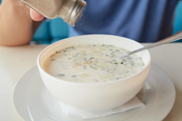 He eats soup okroshka from  round white plate