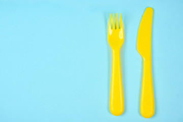 Multicolored plastic dishes on a blue background. The concept of environmental pollution by plastic, ecolog place for text, flat lay