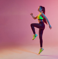 Athletic cool girl trainer teaches group crossfit and work out online training on a bright neon...