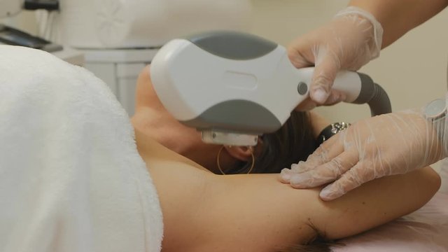 The doctor makes a beautiful woman laser epilation of the armpits .A woman protects her eyes from laser radiation with glasses. The concept of health. 4K