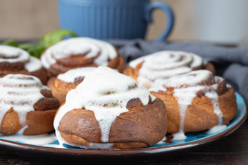 Cinnamon rolls on a plate on a rustic wooden table and a cup of tea. Close view