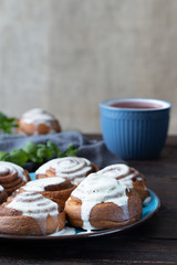 Cinnamon rolls on a plate on a rustic wooden table and a cup of tea. Close view