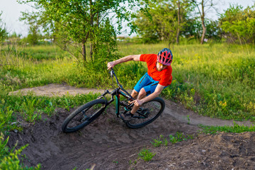 A professional cyclist in a bright orange T-shirt rides under a switchback