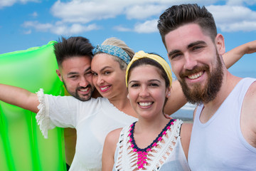 Portrait of four friends, two couples, very smiling and happy enjoying a summer day at the beach.