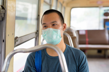 Fototapeta na wymiar Face of young Asian man with mask riding the bus with distance