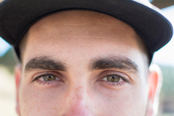 Close-up of the green eyes of a caucasian boy, with a cap.