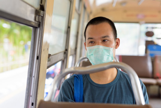 Face Of Young Asian Man With Mask Riding The Bus With Distance