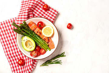 Baked salmon garnished with asparagus and tomatoes with avocado. Top view, overhead, copy space