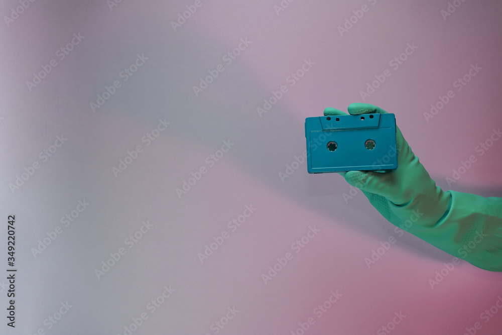 Aufkleber Green Hand holding audio cassette tape in the color light. Beautiful minimal in neon light. Minimalism retro style concept. Background pattern for design.