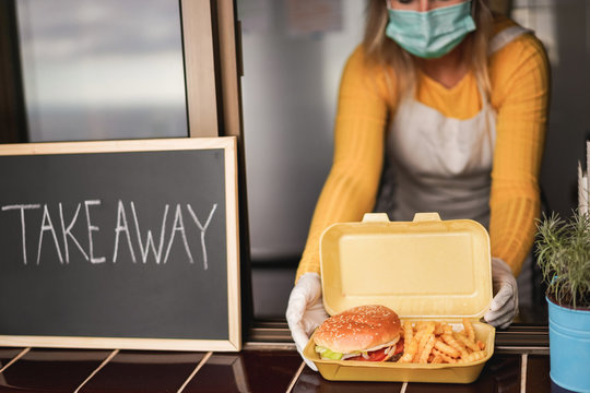 Young Person Preparing Takeaway Food Inside Restaurant While Wearing Face Mask During Coronavirus Outbreak - Worker Inside Kitchen Cooking Fast Food For Delivery Service - Focus On Hamburger And Chips