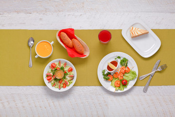 prawns on skewers, grilled. served on lettuce leaves with cherry tomatoes, lemon and hot sauce. in a white round plate. Salad of fresh herbs and figs with tomatoes. Pumpkin soup. Fresh bread. 