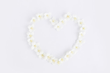 Flat lay in the shape of a heart from jasmine flowers on a white background.
