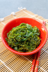 Green fresh oriental seaweed salad served with chopsticks
