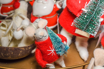 Decoration mouse toy holding a Christmas tree, cute funny ornament for festive season.