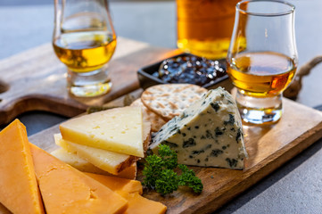 Whiskey and cheese pairing, tasting whisky glasses and plate with sliced cheeses