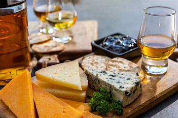 Whiskey and cheese pairing, tasting whisky glasses and plate with sliced cheeses