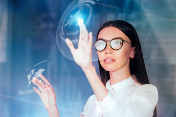 Innovative use of technology in business concept. A young business woman is operating inside an augmented reality, holographic space, monitoring data and analytics with a virtual 3D monitor