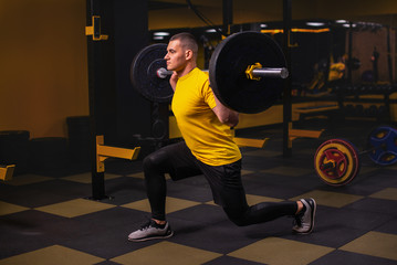 Fototapeta na wymiar Young athlere training lunges with barbells in gym