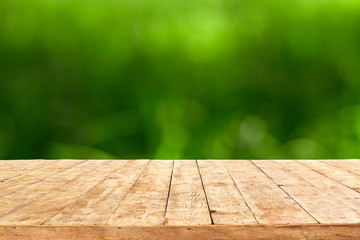 Empty wooden deck table with foliage bokeh background. Ready for product display montage.