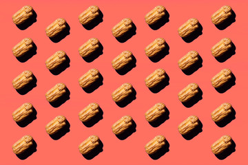 Creative art with yellow Eclair pattern on coral background.Isometric flat lay