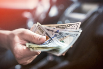 businessman pays for a product or service, gives dollars while sitting in the car.