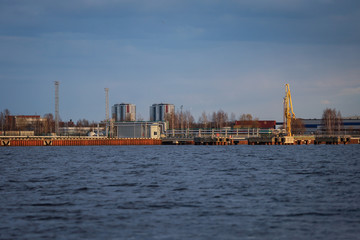 Rural dock view of river Daugava, cranes and city in the background.