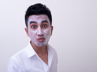 Asian handsome young man applying cream at his face with smiley face, Skin care concept