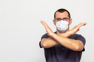 A man with glasses in a protective medical mask standing with crossed hands indoor on white background