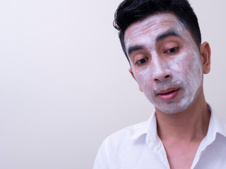 Asian handsome young man applying cream at his face with smiley face, Skin care concept