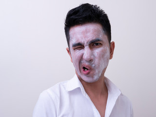 Asian handsome young man applying cream at his face with smiley face, Skin care concept