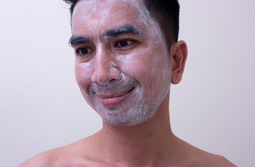 Obraz premium Asian handsome young man applying cream at his face with smiley face, Skin care concept