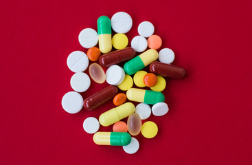 Medical background with pills and capsule on red background.Assorted pharmaceutical medicine pills, tablet. Heap of various assorted medicine tablets and pills different colors. Health care. Top view