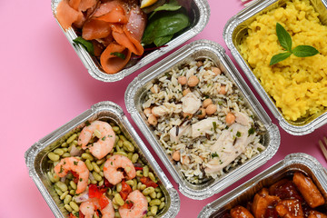 Healthy food  restaurant dish delivery. Take away of fitness meal. Weight loss nutrition in foil boxes. Top view on pink background. service food order online delivery. airline meals and snacks