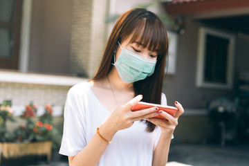 Asian teenager student wear mask for protect virus and using smart phone at outdoor