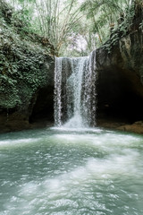 Amazing waterfall Suwat in Gianyar, Bali Indonesia, a stunning island. Jungle waterfall the best cascade in tropical rain forest with rock & turquoise blue pond.