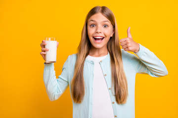 Photo of beautiful little blond lady model hold arm raise thumb finger advising drink milk every morning to be healthy wear casual blue shirt isolated yellow bright color background