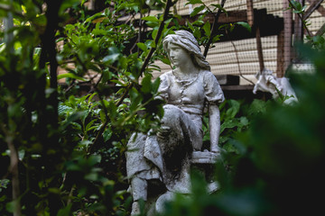 Statue of wooman sitting in the garden.